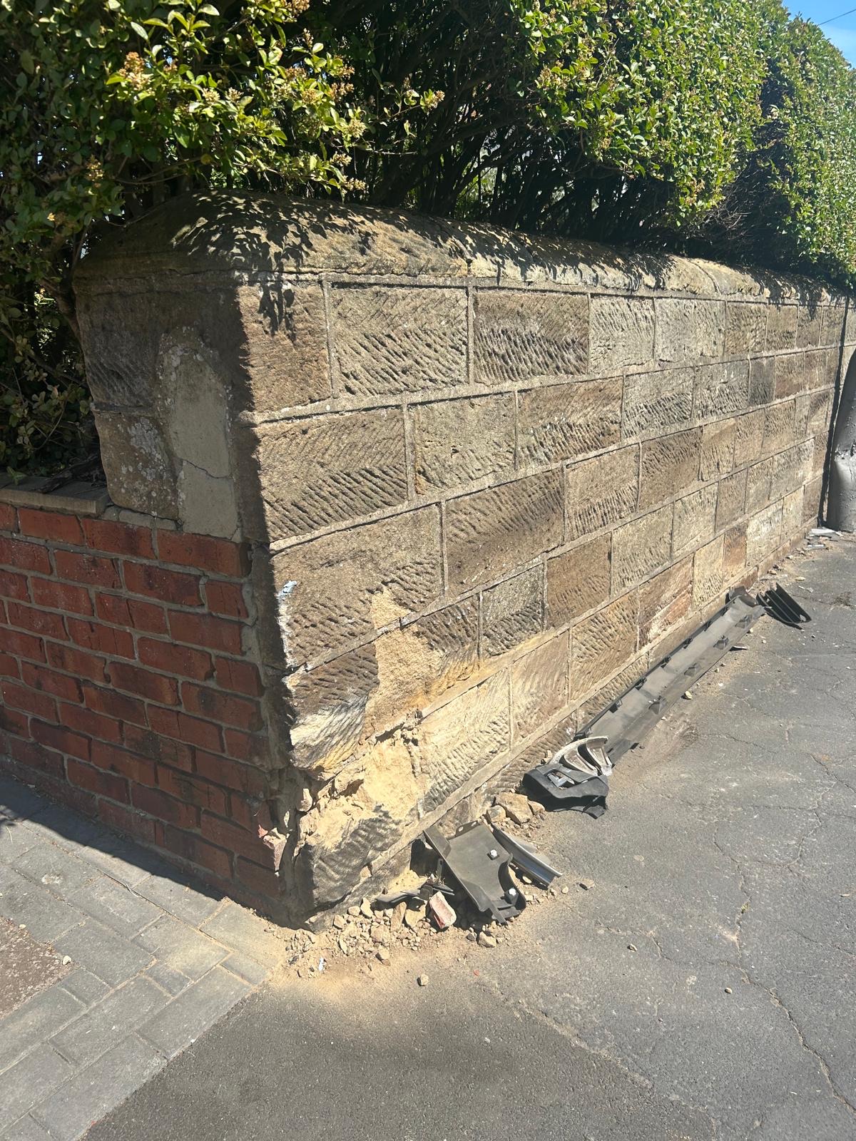 Impact damage to the lower corner of a traditional stone boundary wall in Whitby before the insurance repair